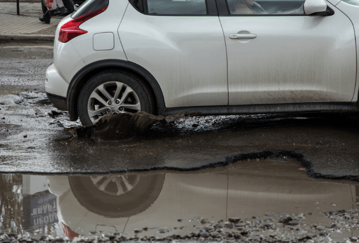 Car driving through pothole full of water