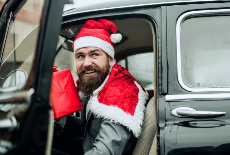 Image of man dressed in Santa hat, getting out of passenger side of car