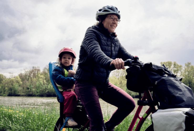 Mother riding bike with child on rear