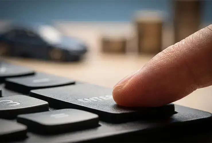 A finger pressing the enter key on a keyboard