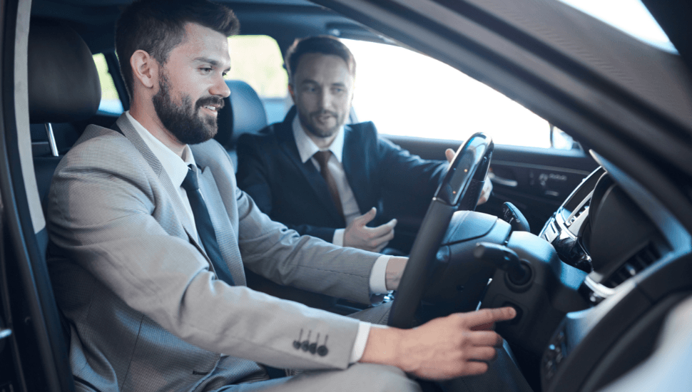 Man in suit test-driving car