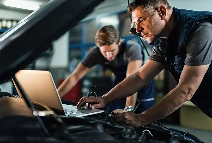 Mechanics working on a car using a software diagnostics tool