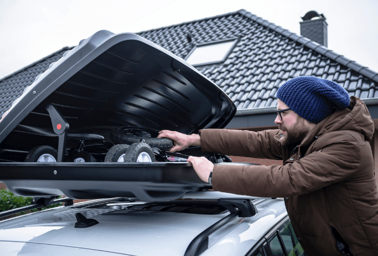 Man putting items into car roof box