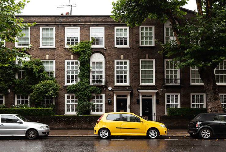 Yellow car parked in front of historical house
