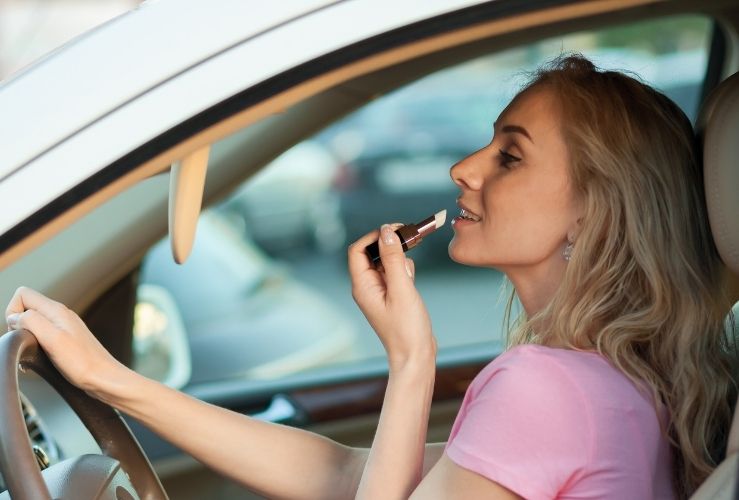 Woman applying lipstick whilst driving