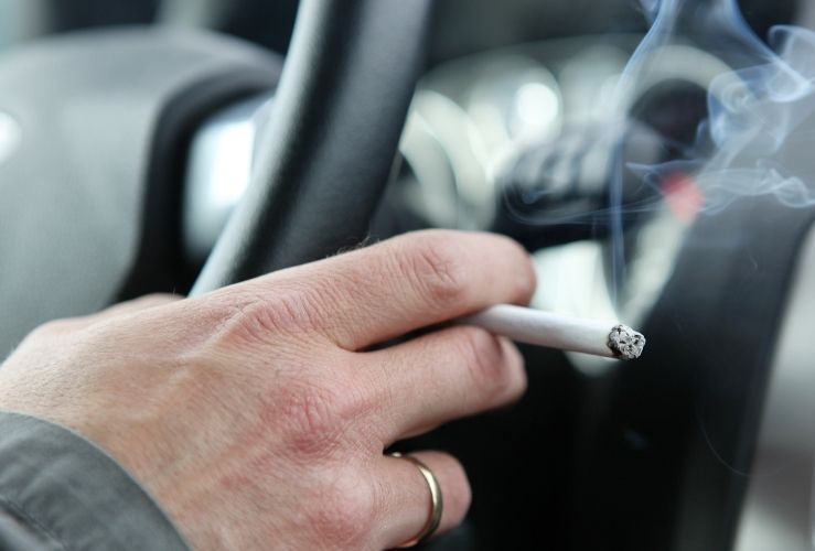 Person holding lit cigarette whilst driving car