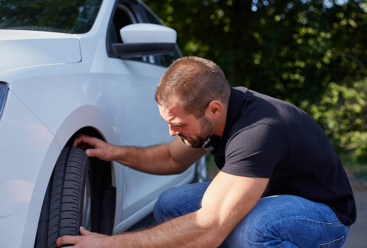 Man checking tires on new car