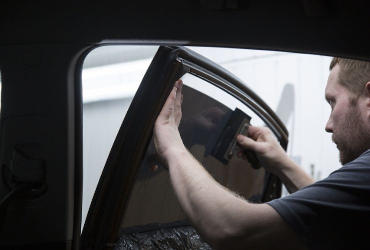 Image of man applying tint to car windows