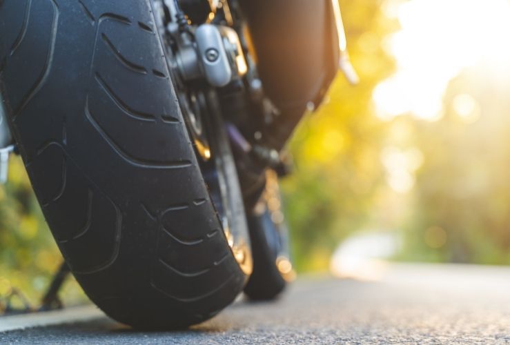 Back wheel of motorcycle pictured parked at side of road