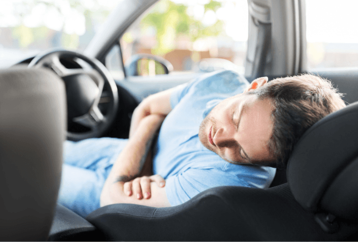 Man asleep in driver seat of car