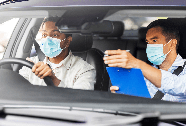 Driving test examiner and pupil wearing face masks on driving test