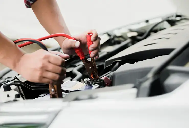 A person jump starting a car battery