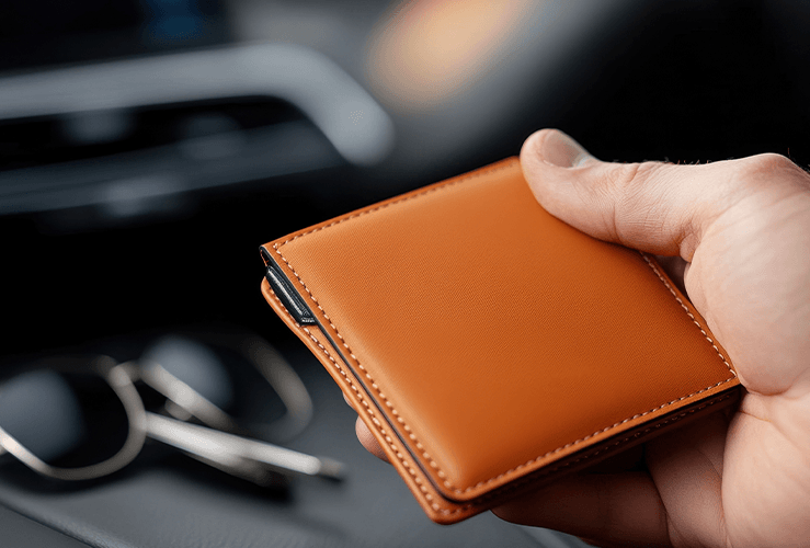 A hand holding a brown leather wallet