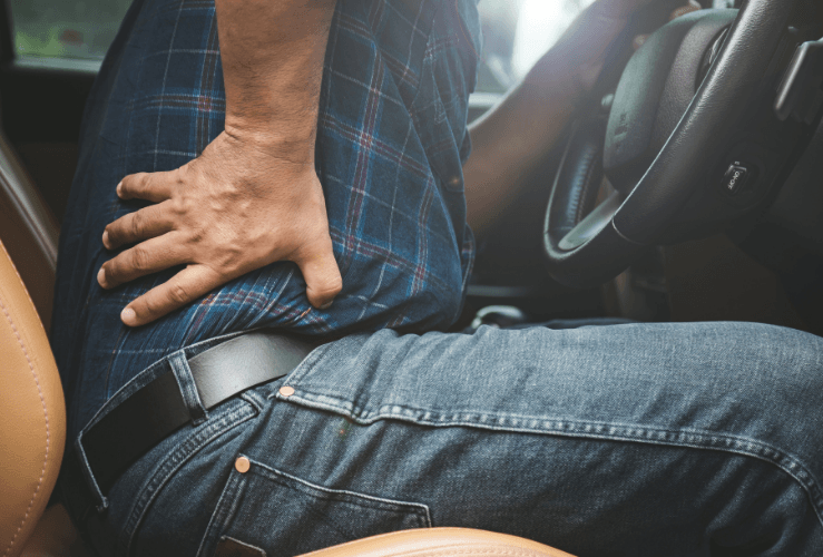 Man holding back in pain, whilst sitting in car