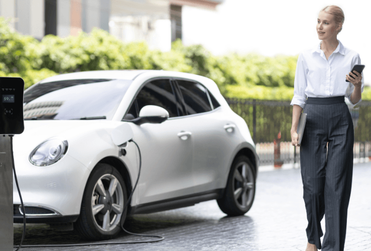 Business woman walking whilst car charging