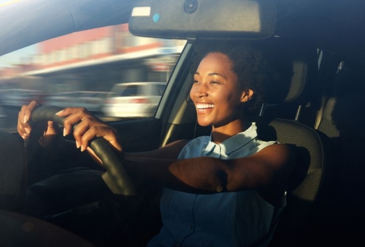 Young, happy woman driving a car