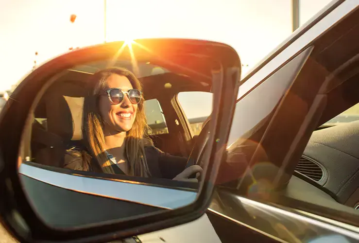 A woman driving a car looking happy