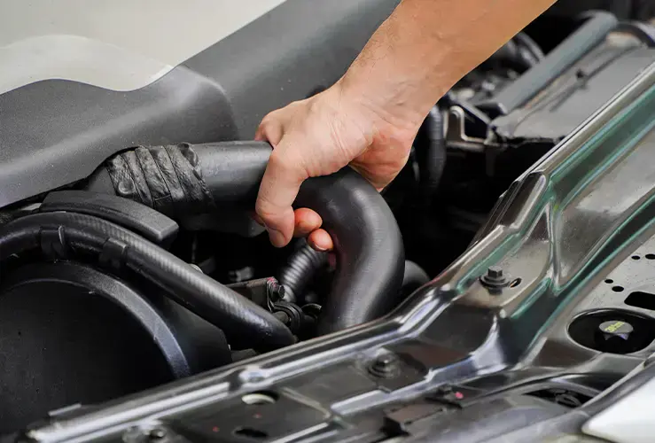 A mechanic fixing a hose in a car