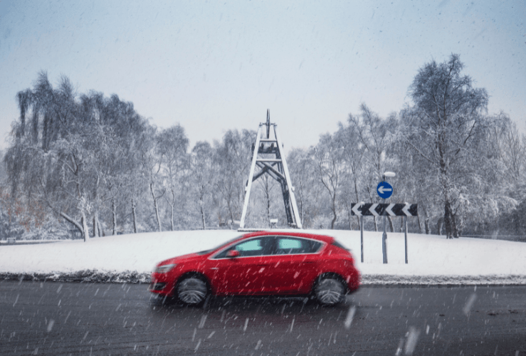 Car driving around roundabout in snowy weather UK