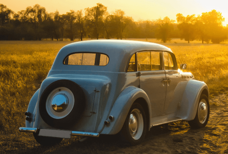 Classic car in field at sunset