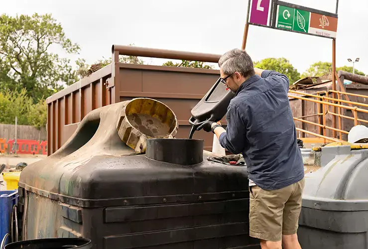 A person disposing of oil at a recycling centre