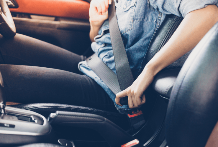 Woman fastening seatbelt in car
