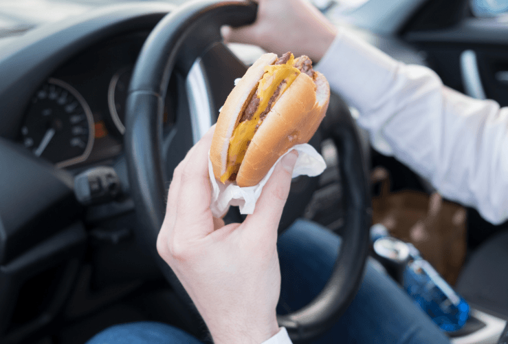 Image of a man eating a burger whilst driving