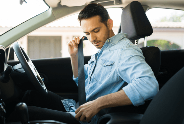 Male driver putting on car seatbelt