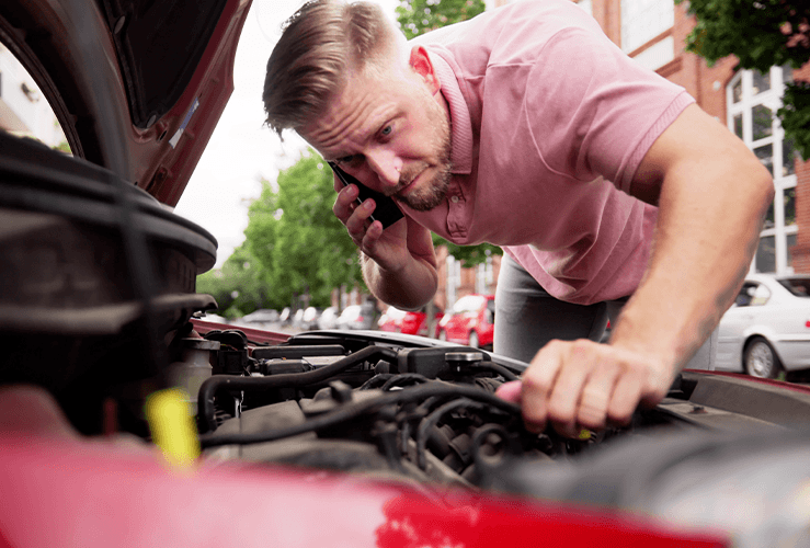 A man looking in a car engine bay