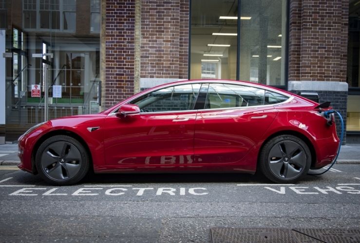  A red Tesla Model 3 parked and charging on city street