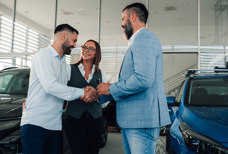 People shaking hands in a car dealership